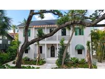 Elegant two-story home featuring a balcony, black-framed windows, and beautifully landscaped front yard with tropical foliage at 1658 Bonita Ln, Sarasota, FL 34239