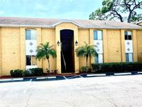 Inviting two-story condo with mature palm trees, dark metal gate, and an assigned parking space in front at 1959 Toucan Way # 206, Sarasota, FL 34232