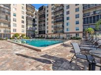 A swimming pool outside a condo building features a brick deck and patio seating at 2901 26Th W St # 204, Bradenton, FL 34205