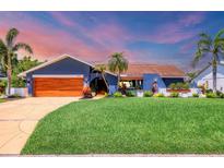 Charming single-story home featuring vibrant blue exterior, lush lawn, beautiful landscaping, and a wooden garage door at 3636 Torrey Pines Blvd, Sarasota, FL 34238