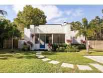 Charming white home features a blue front door, lush landscaping, and a well-manicured lawn at 522 31St W St, Bradenton, FL 34205