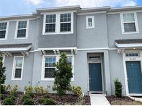 Modern townhome featuring a gray exterior, well-kept landscaping, and a bright blue front door at 6358 Fairmont Ln, Palmetto, FL 34221