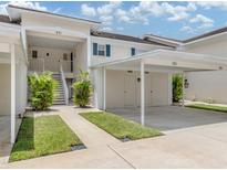 Inviting condo featuring covered parking, a staircase to the entrance, and lush tropical landscaping at 821 Montrose Dr # 103, Venice, FL 34293
