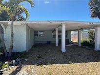 A single-story home with a covered outdoor space and a gravel yard awaits landscaping at 13434 1St St E, Madeira Beach, FL 33708