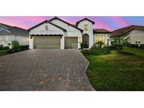 Charming home showcasing a paver driveway, a two-car garage, and lush landscaping at 13513 Deep Blue Pl, Bradenton, FL 34211