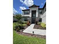 Elegant home features a stone facade, well-manicured lawn, and inviting walkway leading to the front door at 16231 Tradewind Ter, Bradenton, FL 34211
