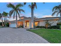 Stunning exterior with a paver driveway and lush landscaping with palm trees lining the entrance of this beautiful home at 571 Birdie Ln, Longboat Key, FL 34228