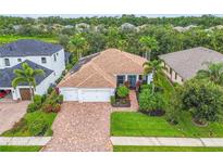 Well-maintained home featuring a brick driveway, two-car garage, and lush landscaping enhancing its curb appeal at 616 Dogwood Run, Bradenton, FL 34212