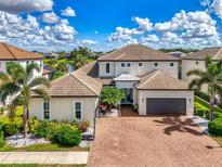Beautiful two-story home featuring lush landscaping, a brick driveway, and a two-car garage at 6318 Rivo Lakes Blvd, Sarasota, FL 34241