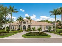 Stunning home with lush landscaping, a circular driveway, and a beautiful tile roof against a backdrop of blue skies at 7144 Ashland Gln, Lakewood Ranch, FL 34202
