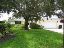 Charming single-story home featuring a lush green lawn and mature shade tree at 7157 Fairway Bend Cir, Sarasota, FL 34243
