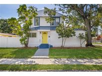 Charming home with a bright yellow door, complemented by lush landscaping and mature trees at 719 22Nd W St, Bradenton, FL 34205