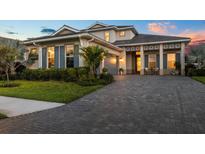 Stunning two-story home with a paved driveway, manicured lawn, and charming architectural details at sunset at 8209 Redonda Loop, Lakewood Ranch, FL 34202