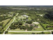 Sprawling estate with multiple buildings, mature trees, serene pond, and equestrian facilities nestled in a lush, green landscape at 21210 77Th E Ave, Bradenton, FL 34202
