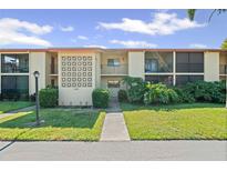 Well-manicured condo building with manicured lawn and tropical plants under a bright sky at 2415 Bayshore Gardens Pkwy # 2, Bradenton, FL 34207