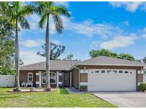 Charming home featuring lush lawn, mature palms, and a two-car garage at 2761 Feiffer Cir, Sarasota, FL 34235