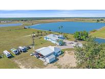 Stunning aerial view of a lakefront property with a spacious home and a large outbuilding for RV parking at 29527 Leah Rd, Punta Gorda, FL 33982
