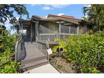 Charming home featuring a screened-in deck with wooden stairs and lush, mature landscaping at 4333 Trails Dr # 10-1, Sarasota, FL 34232