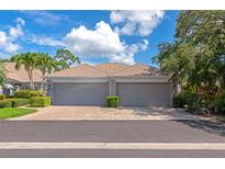 Attached garages with gray doors and a brick paver driveway beneath a sunny, partly cloudy sky at 5417 Champagne # 63, Sarasota, FL 34235