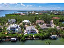Waterfront homes with private docks nestled in lush greenery overlooking the bay in a sunny, tropical locale at 663 Penfield St, Longboat Key, FL 34228
