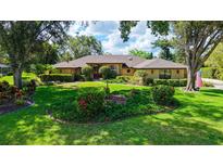 Beautifully landscaped front yard of tan single-story home with mature trees, lush lawn and manicured flower beds at 7426 Weeping Willow Blvd, Sarasota, FL 34241