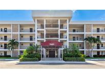 Condo building featuring a covered entrance, well-maintained landscaping and palm trees at 7461 W Country Club N Dr # 206, Sarasota, FL 34243
