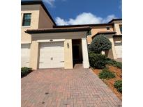 Two story home showcasing the front exterior with a red brick driveway and an attached two car garage at 10054 Crooked Creek Dr # 201, Venice, FL 34293