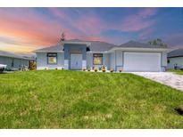 Charming single-story home featuring a well-manicured lawn and a two-car garage at 10443 Riverside Rd, Port Charlotte, FL 33981
