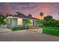 Charming single-story home featuring a cozy front porch, lush lawn, and beautiful landscaping at 1051 Indian Beach Dr, Sarasota, FL 34234