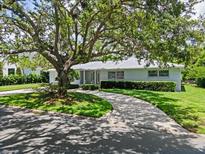 Charming single-story home with a well-maintained front yard and circular driveway shaded by a mature tree at 1541 Flower Dr, Sarasota, FL 34239