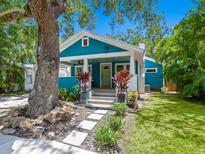 Charming blue bungalow featuring a covered porch, stone pathway, and lush landscaping at 1732 6Th St, Sarasota, FL 34236