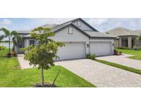 Charming, light gray home with a two-car garage, brick paved driveway and well-manicured landscaping at 17823 Cherished Loop, Bradenton, FL 34211