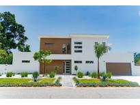Modern two-story home featuring wood accents, a landscaped yard, and a striking entrance at 2124 Clematis Pl, Sarasota, FL 34239