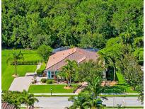 Beautifully landscaped home featuring a terracotta roof and lush, mature trees at 336 165Th Ne Ct, Bradenton, FL 34212