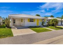 Charming single-story home featuring a white tile roof, yellow shutters, and well-maintained front lawn at 564 Spanish N Dr, Longboat Key, FL 34228