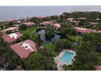 Aerial view of community featuring a pool, lake, landscaping, and condo buildings with red roofs at 6472 Seagull Dr # 301, Bradenton, FL 34210