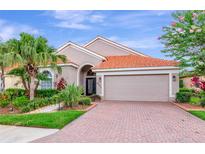 Charming single-story home featuring a red tile roof, brick driveway, and lush tropical landscaping at 6845 74Th Street E Cir, Bradenton, FL 34203