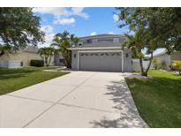 Two-story home with well-manicured lawn, palm trees, and a spacious concrete driveway leading to a two-car garage at 11839 Shrewsbury Ln, Parrish, FL 34219