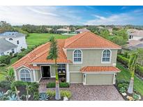 Beautiful two-story home featuring a tile roof, arched windows, and a lush, tropical landscape at 12814 Daisy Pl, Bradenton, FL 34212