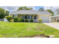 Charming single-story home with a well-manicured lawn and cozy front porch featuring hanging flower baskets at 1778 N Salford Blvd, North Port, FL 34286