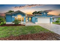 Charming blue home featuring a well-manicured lawn, beautiful brick driveway, and a welcoming front entrance at 220 39Th Ne St, Bradenton, FL 34208
