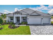 Charming one-story home with a tile roof, manicured lawn, paver driveway, and three car garage at 3512 Cross Creek Pkwy, Parrish, FL 34219