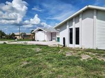 Exterior view of a white stucco home with green lawn and bright blue sky at 4354 Rock Creek Dr, Port Charlotte, FL 33948