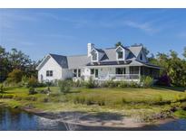 Charming white home featuring a welcoming front porch and serene pond with fountain at 4888 Old Ranch Rd, Sarasota, FL 34241