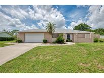 Charming one-story home with a well-manicured lawn, mature landscaping and a two-car garage at 5124 Palm Aire Dr, Sarasota, FL 34243