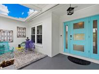 Inviting front porch with a bright blue door, light stone and colorful patio seating at 538 Magellan Dr, Sarasota, FL 34243