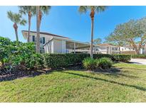 Condominium exterior with private carport, mature landscaping, and Spanish tile roof at 803 Montrose Dr # 201, Venice, FL 34293