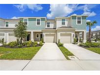 Two-story townhome featuring a single-car garage, neutral paint, and manicured landscaping at 8705 Winter Breeze Way, Sarasota, FL 34241