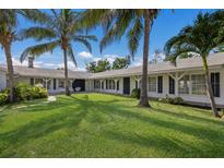 Stunning white home with a lush green lawn and mature palm trees, creating a serene tropical oasis at 1408 99Th Nw St, Bradenton, FL 34209
