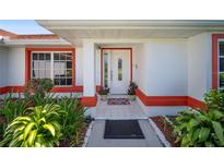 Inviting front entrance with decorative glass door and colorful landscaping at 22378 Peachland Blvd, Port Charlotte, FL 33954